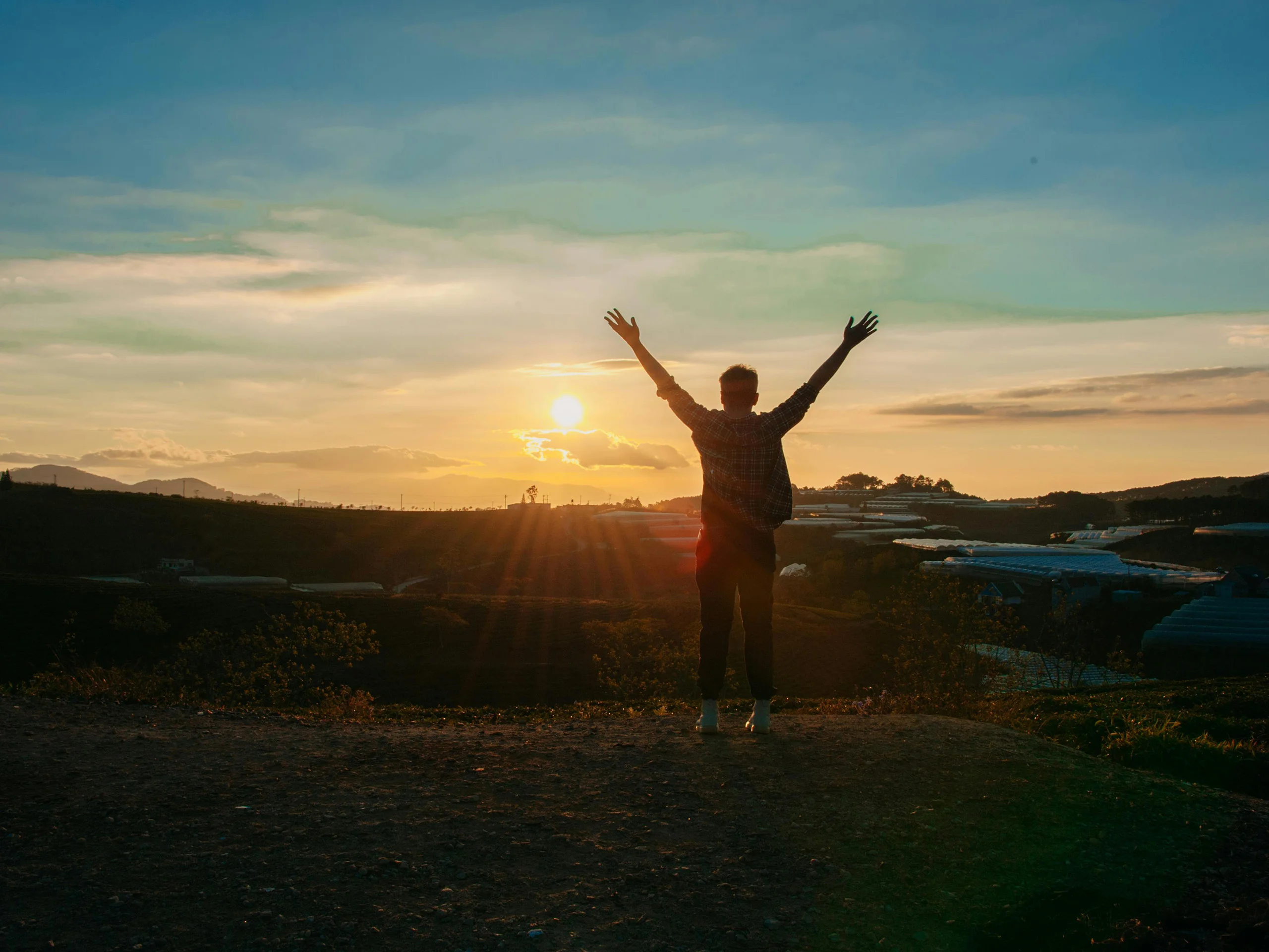 Man with arms up looking at sunset
